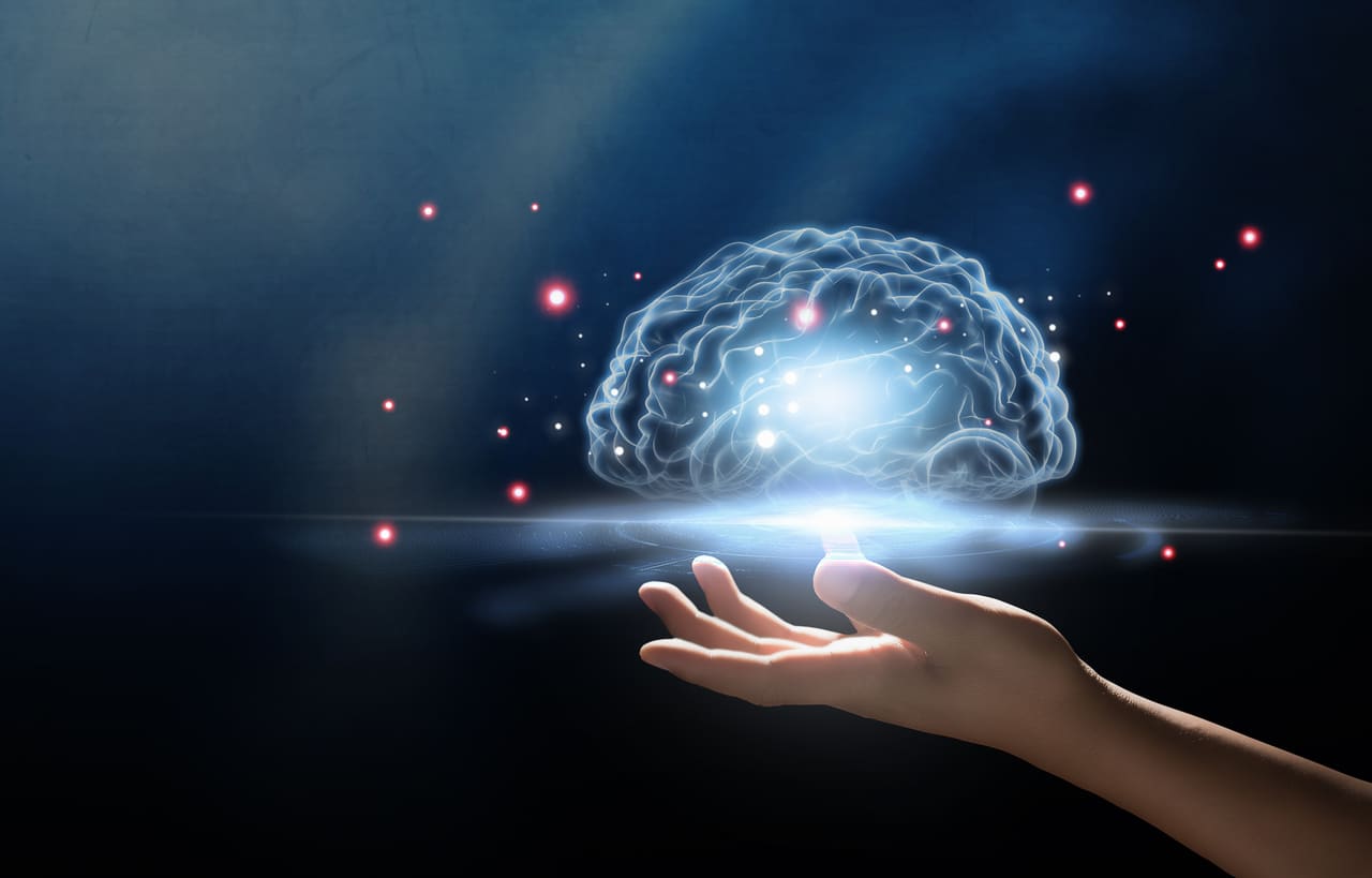 Digital Composite Image Of Hand Holding Illuminated Digital Brain Mid-Air Against Black Background